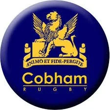 The logo of Cobham Rugby featuring a lion and a griffin with a banner saying 'As I Move and Fide Perligte' in yellow and white colors.