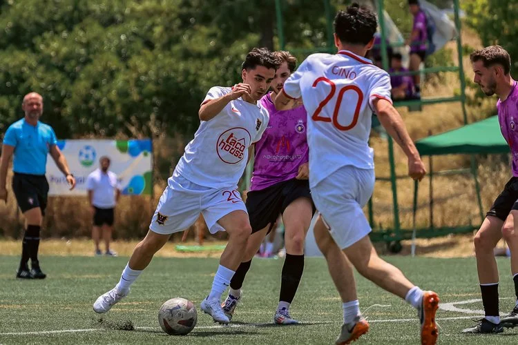 Football players competing for the ball during a match at the Portugal Summer Football Cup 2025.