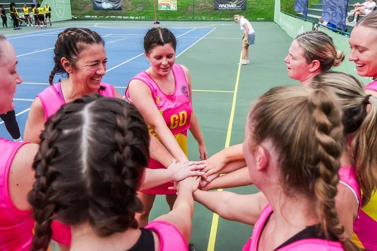 A women's netball team in pink huddling.jpg