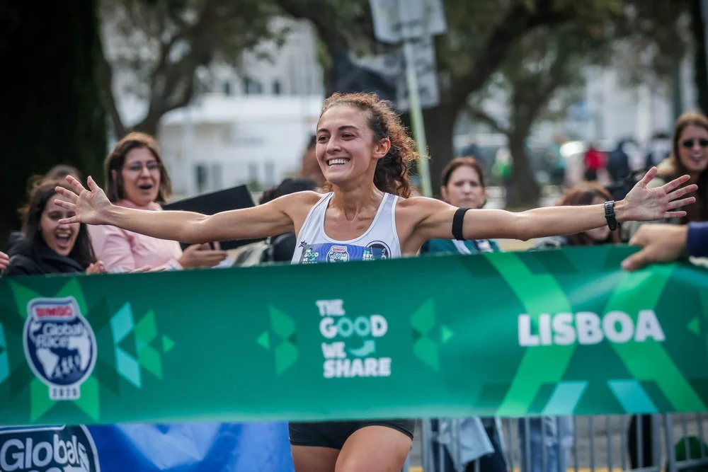 Runner celebrating as she crosses the finish line at the Bimbo Global Race in Lisbon.