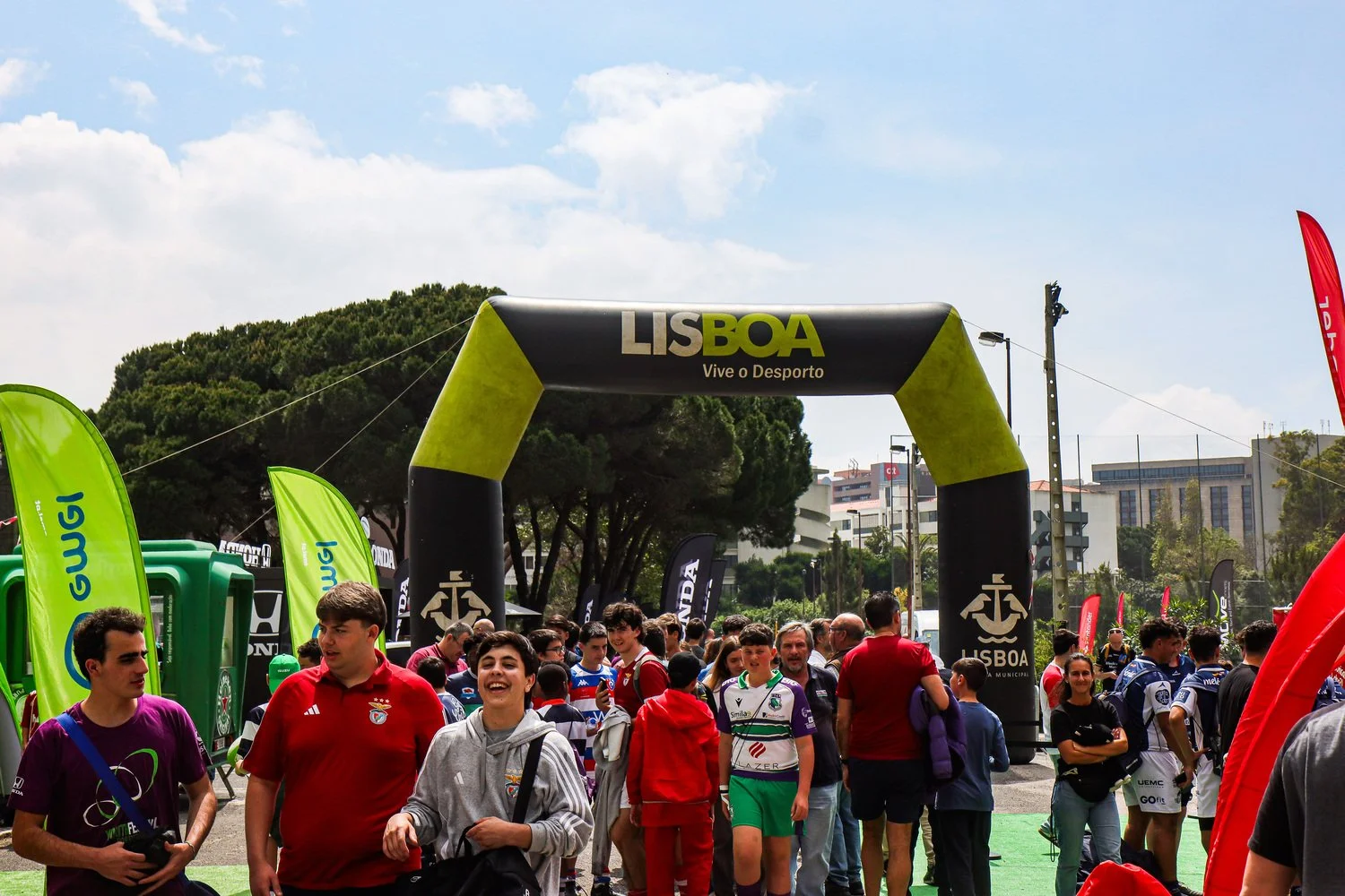 Participants and spectators entering the Portugal Rugby Youth Festival venue in Lisbon, with the event arch and sponsor flags visible.