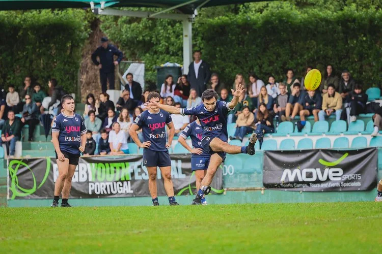Youth rugby player taking a kick during a match at the Portugal Rugby Youth Festival Autumn Series 2025, with spectators in the stands.