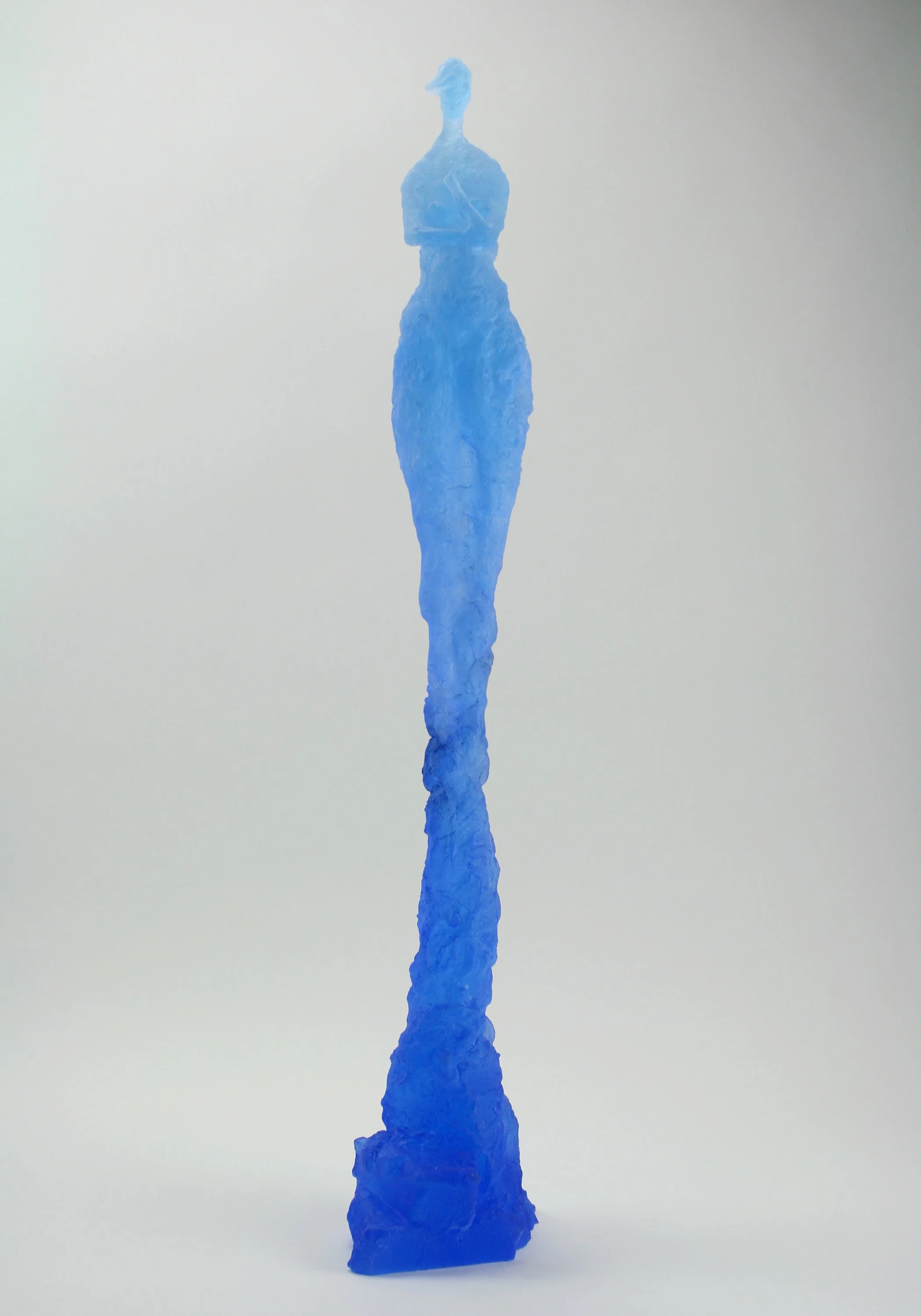 Blue sculpture shaped like a person with crossed arms, standing on a rectangular base, against a plain background.