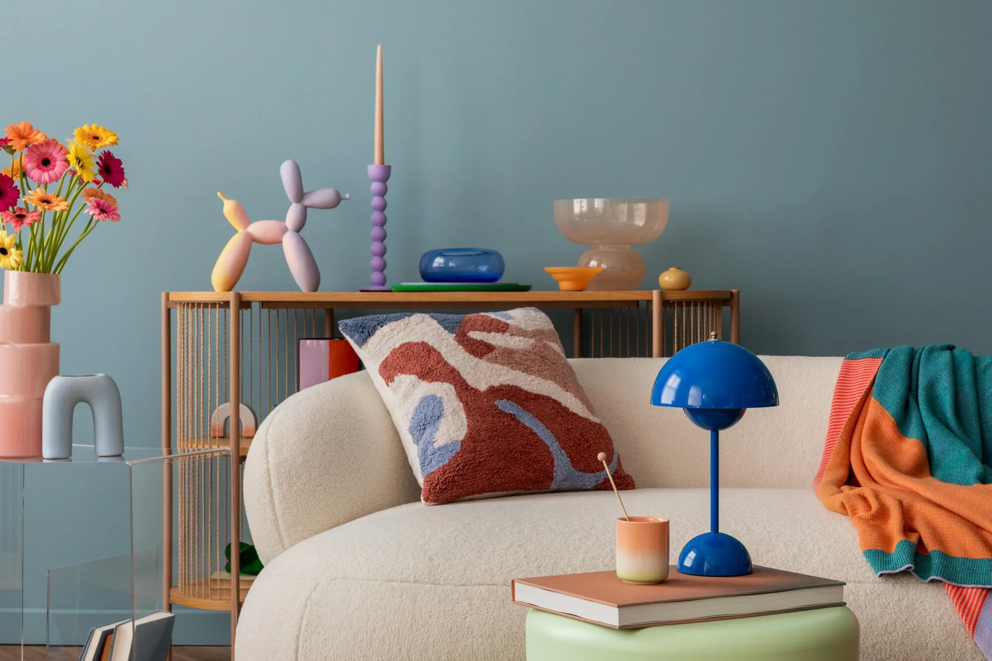 Gemütliches Wohnzimmer mit bunter Dekoration, Blumenstrauß, Kissen, Tischlampe und stilvollen Vasen
