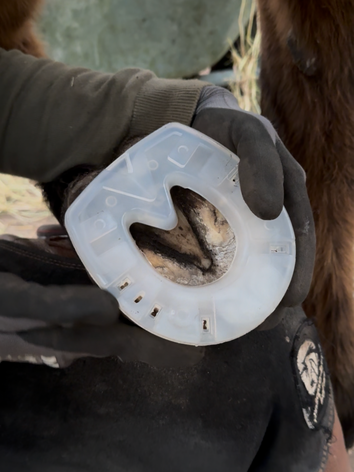 Close-up van een persoon die een paardenzadeltui vastheeft, met zichtbaar insleepmechanisme en modder erin