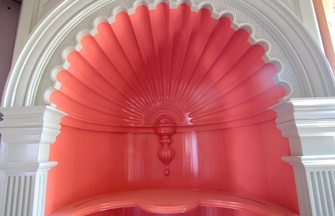 Interior of a decorative, pink shell-shaped architectural feature with white accents and a central purple ornament.