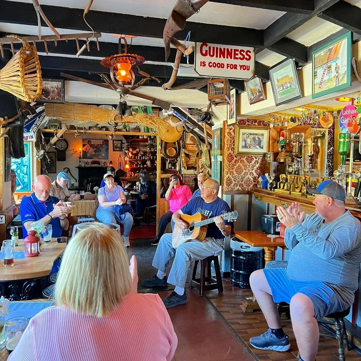 People enjoying live music performance in a cozy pub decorated with vintage signs and memorabilia.