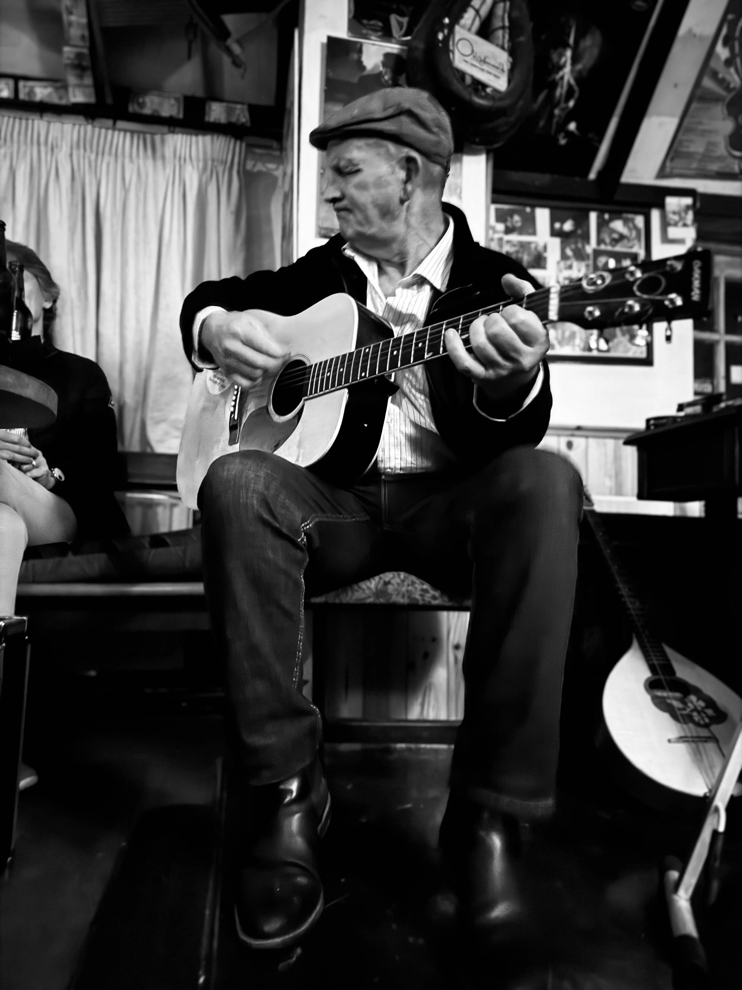 Black and white photo of a man in a cap playing guitar