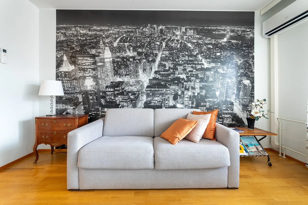 Elokuvateemainen tapetti, joka esittää kaupungin siluetin yöllä, aina sohvapöytään asti.