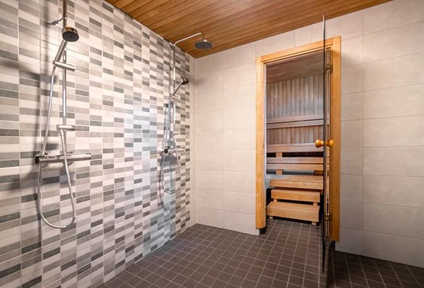Kaksi suihkualtasta kylpyhuoneessa, erillinen sauna ovi vieressä.