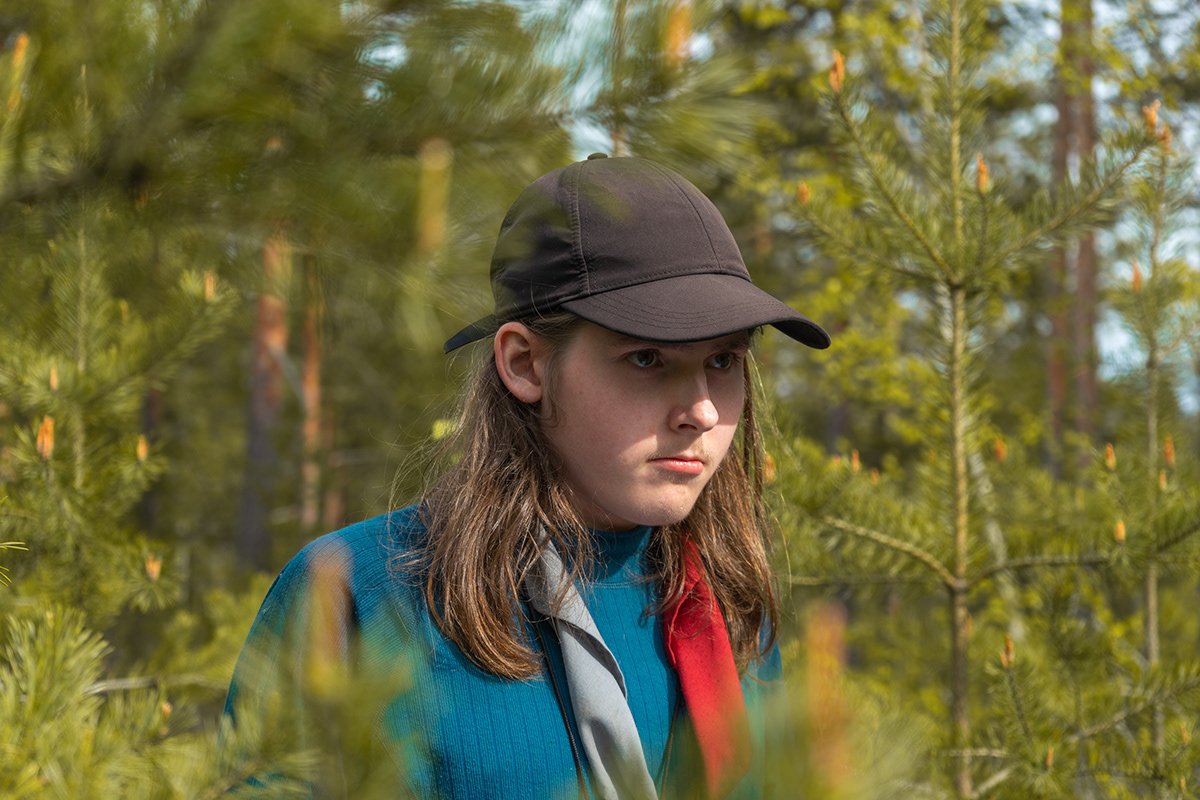 Nuori nainen metsässä, pitelee puuta kädessään