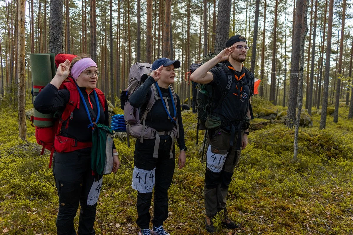 Kolme ihmistä seisoo metsässä, suorittaa sotilaan vakioriituaali.