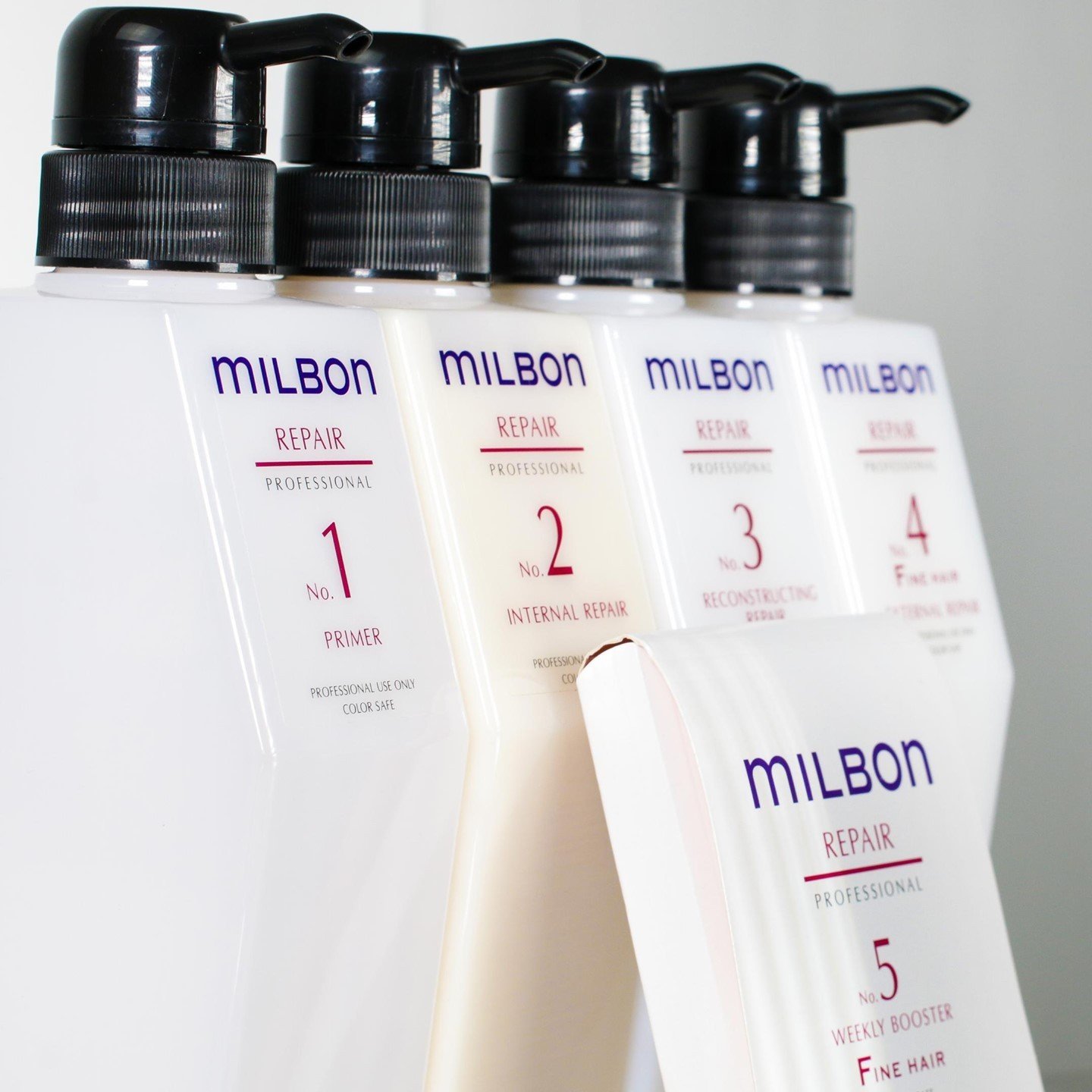 A set of four Milbon Repair Professional hair treatment bottles with black pump tops, labeled from 1 to 4, arranged in a row. The fifth bottle, labeled No. 5, is placed in front of the others.