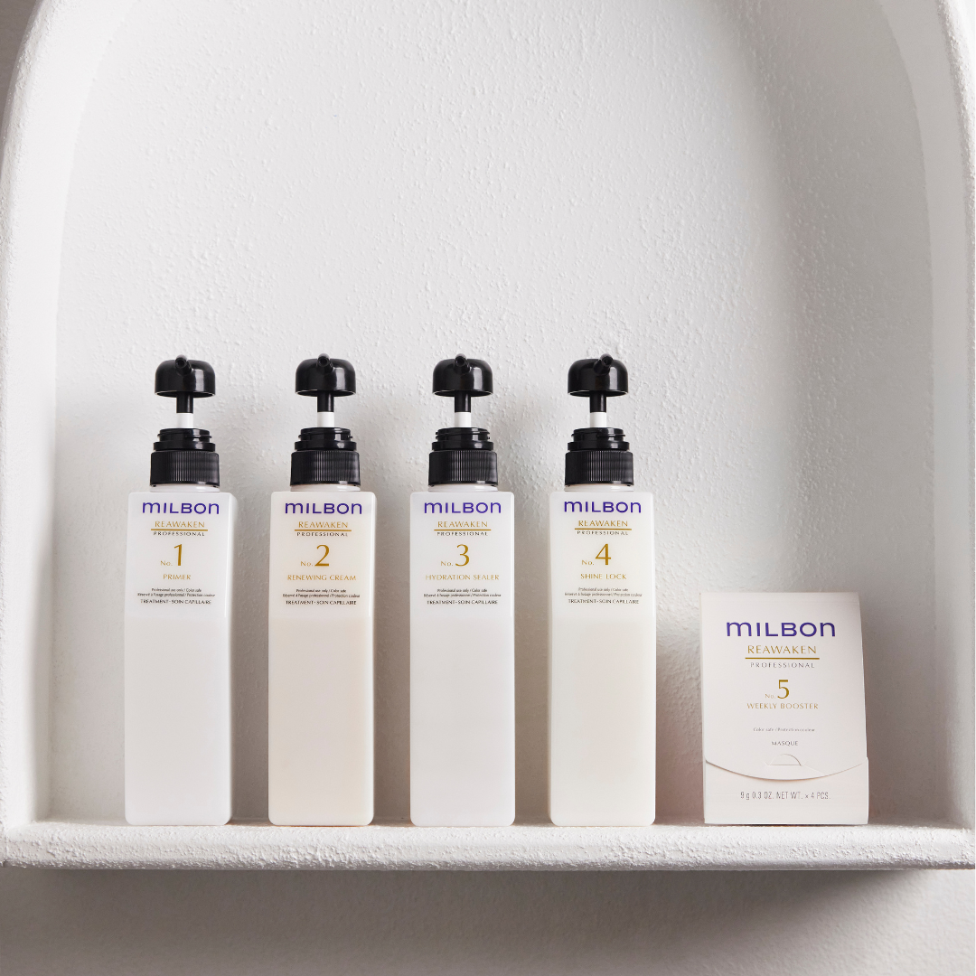 Four bottles of Milbon Reawaken Professional hair treatment products labeled 1 Prime, 2 Renewing Cream, 3 Hydration Sealer, and 4 Shine Lock, along with a box labeled 5 Weekly Booster.