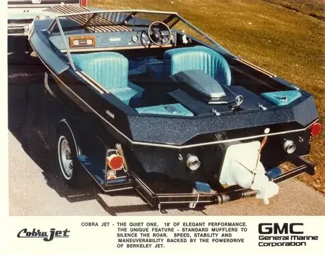 A vintage Cobra Jet speedboat with teal interior, black exterior, and outboard motor, parked on pavement.