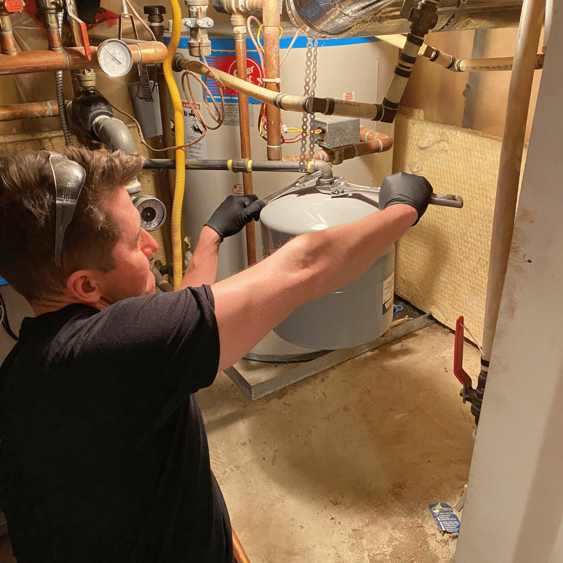 Eric of Bluestone Plumbing servicing a water heater in a Vancouver home.