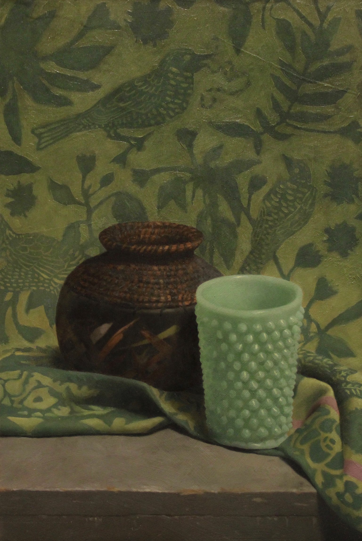 Painting of two ceramic vases, one brown and woven, the other pale green with raised dots, resting on a colorful cloth in front of a green background with bird and leaf patterns.