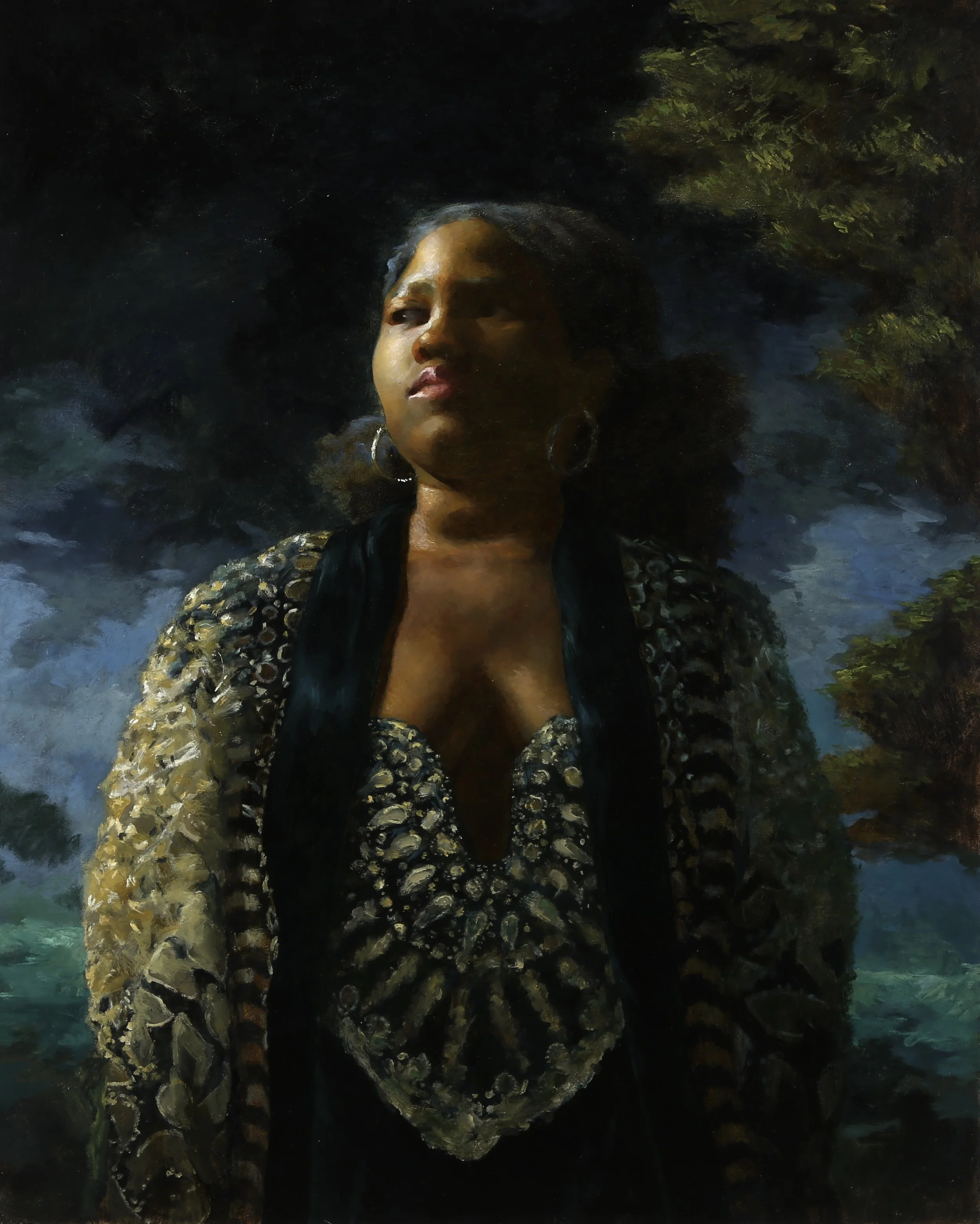 A portrait of a woman with dark hair, wearing hoop earrings and an Elie Saab top, standing against a background of trees and a cloudy sky.