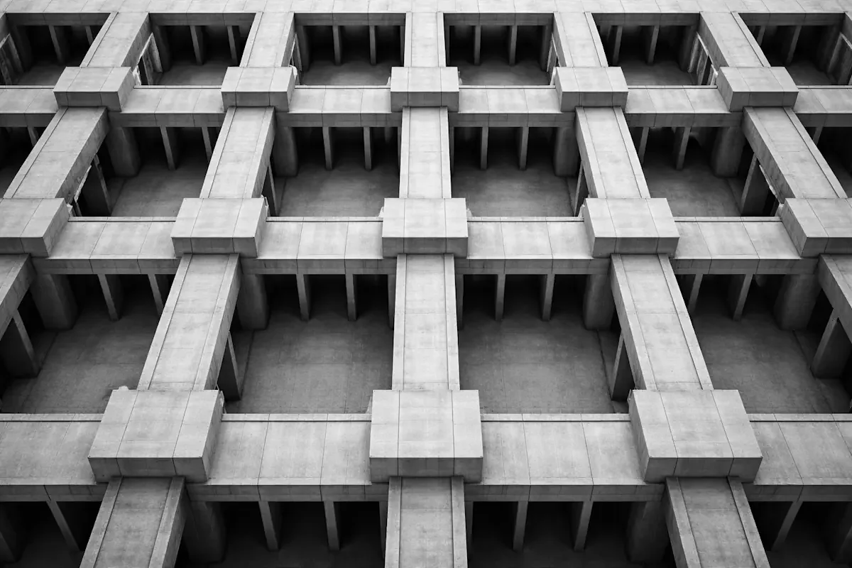 Aerial view of a modular concrete complex with repeating connected blocks — the operating system that keeps surfacing problems live