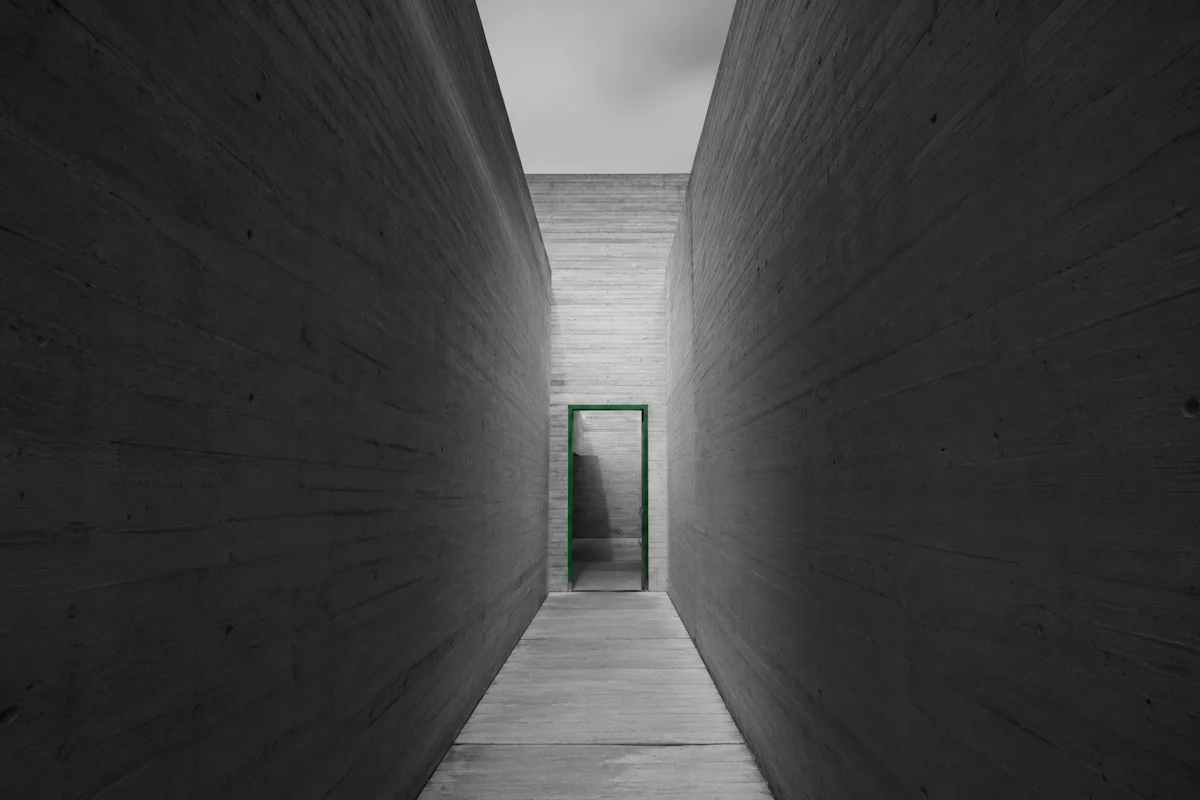 Narrow concrete corridor converging on a single doorway — why most small businesses are stuck at Level 1 or Level 2