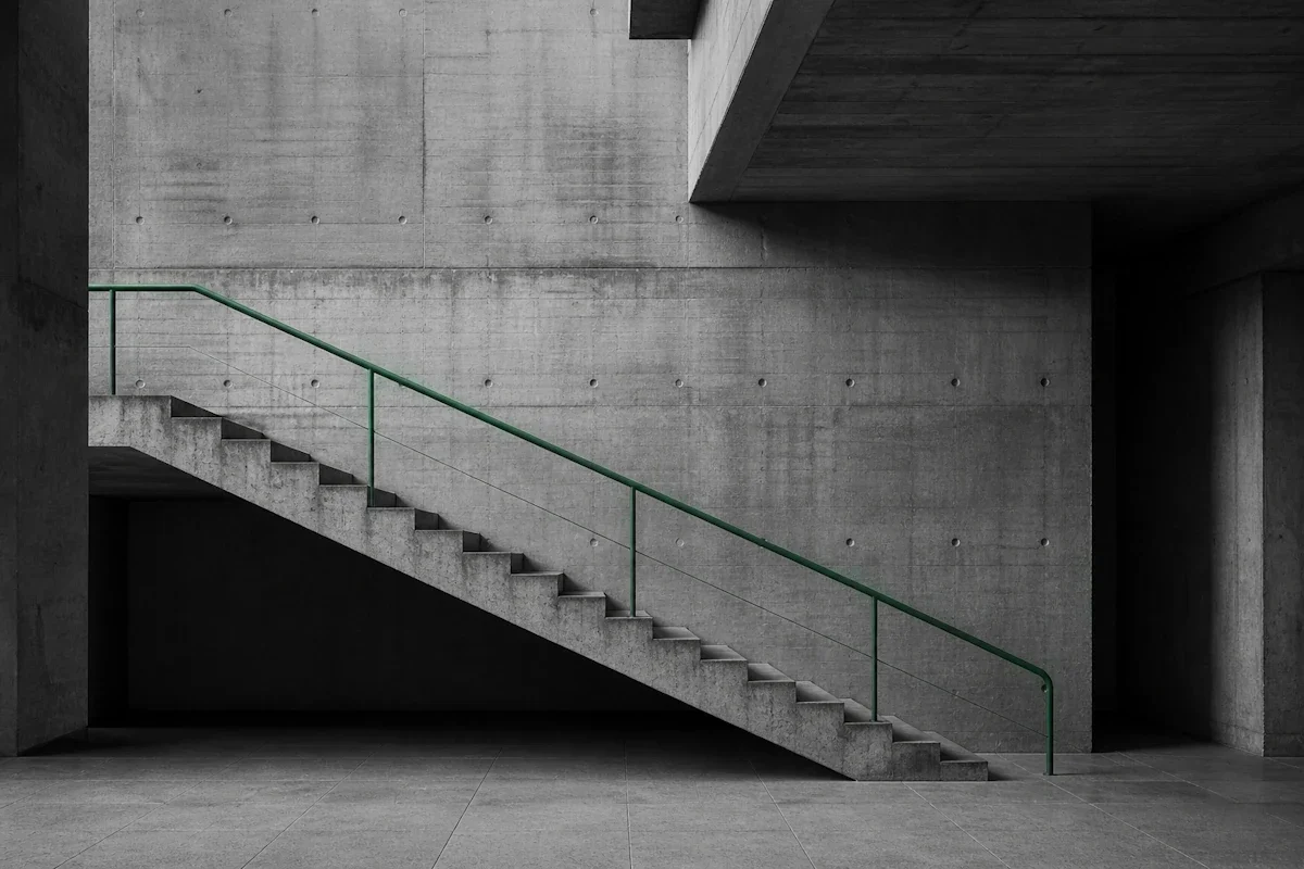 Brutalist concrete staircase connecting two floor levels — the judgement layer and the operational layer