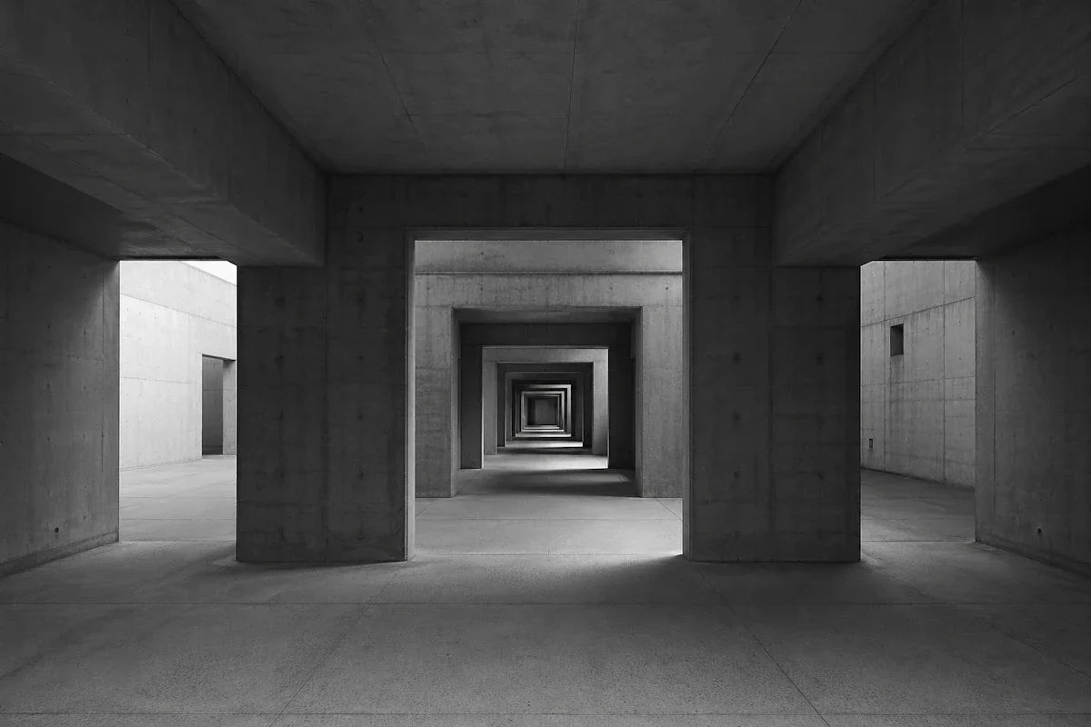 Brutalist concrete corridor branching into multiple openings — the five modes of stepping back