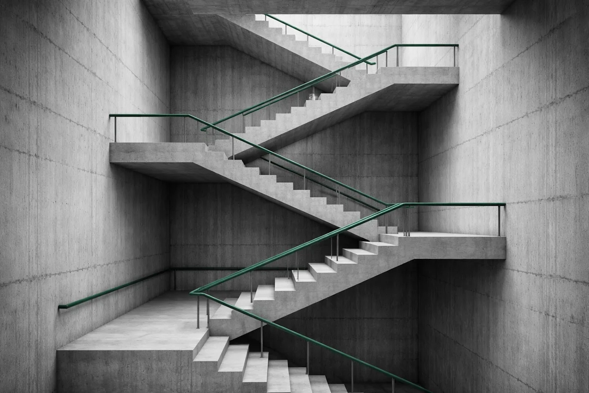 Concrete staircase ascending through four levels with a green-accented handrail — the maturity path from simple workspace to intelligent, automated business.