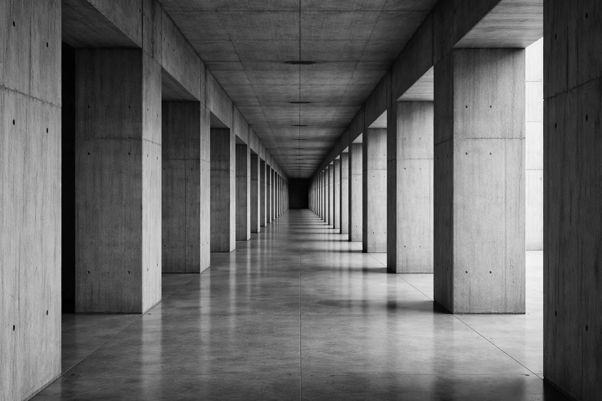 Long concrete corridor with rhythmic repeating columns in diminishing perspective — the daily and weekly operational rhythm that drives a business operating system.