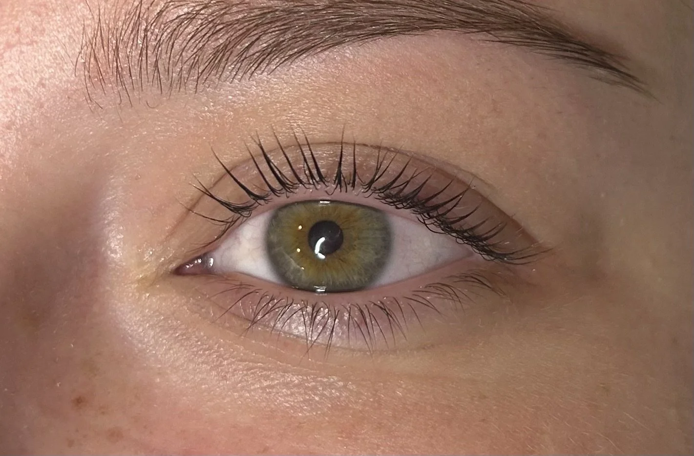 Dichtbijzicht van een menselijk oog met groenbruine iris en wijde pupil.