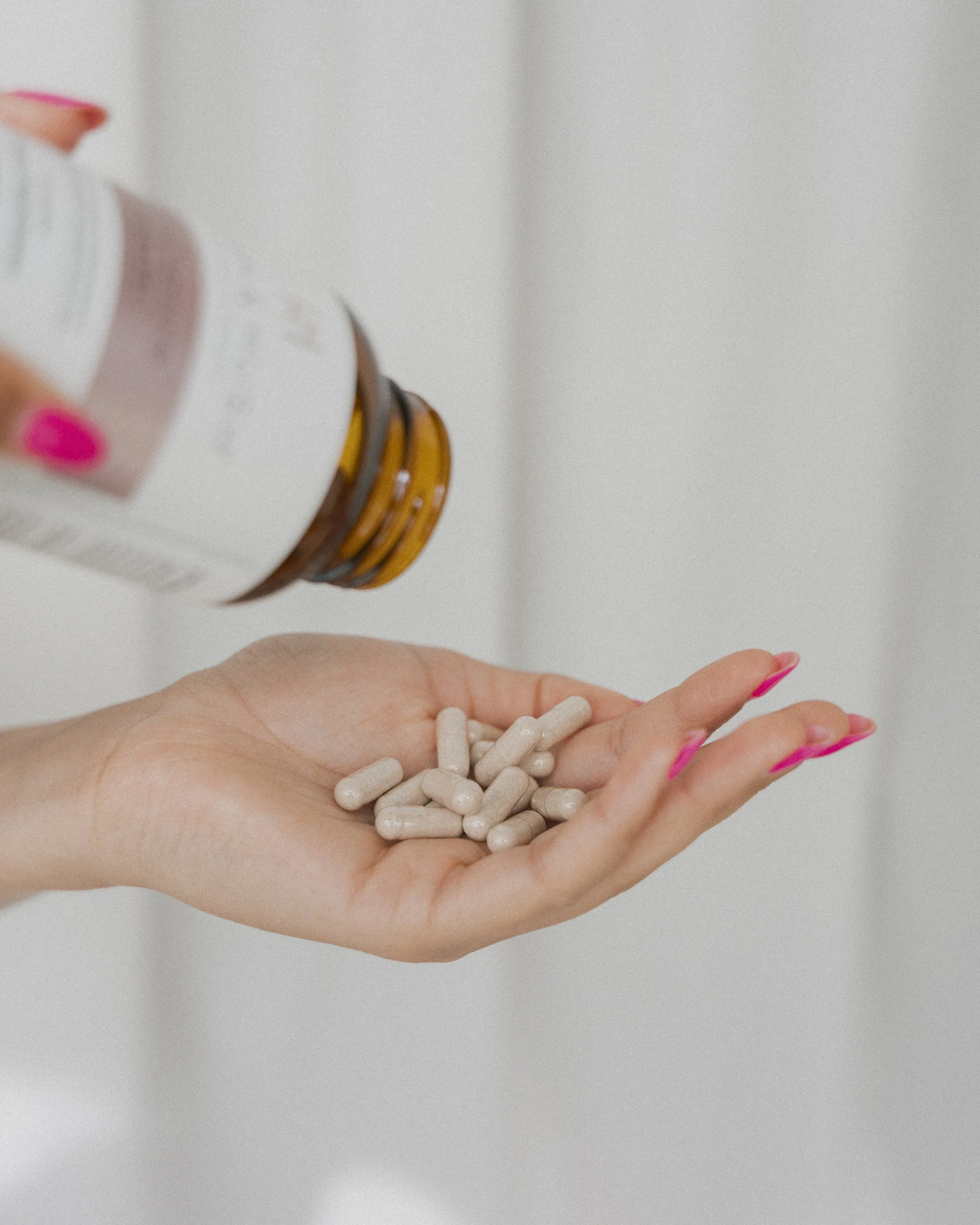 Persoon die wit capsule-slanke pillen uit een flesje giet.