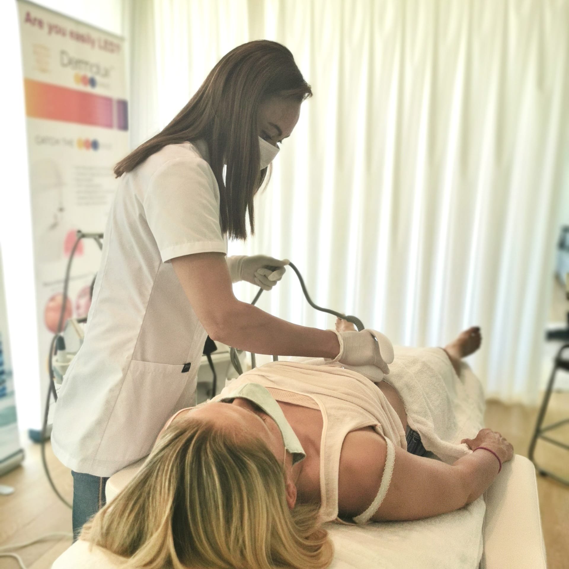 Vrouw die een medische procedure uitvoert op een slapende vrouw op een behandeltafel.