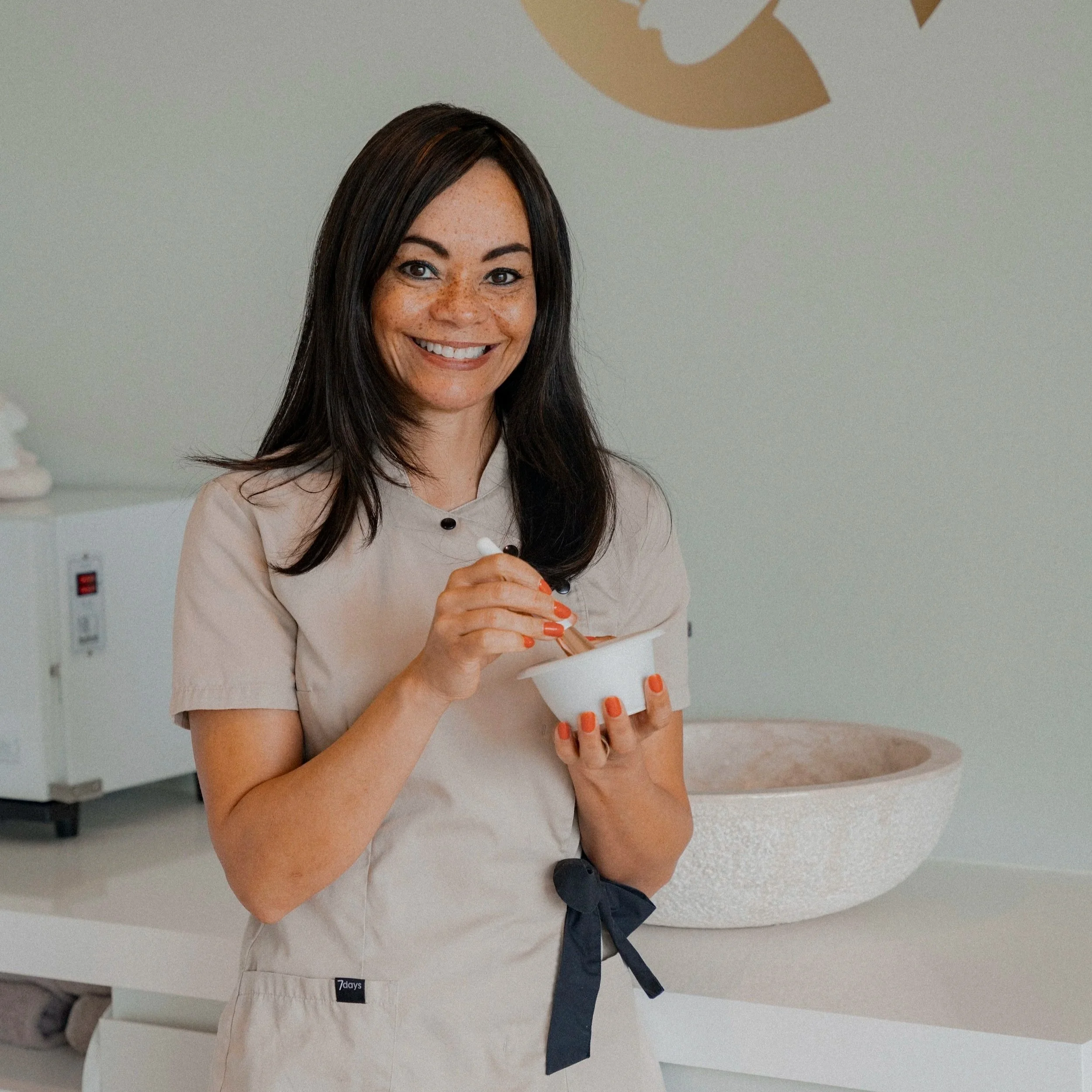 Vrouw in een beige uniform die ijs of yoghurt serveert in een witte kom in een wellness- of spa-omgeving.