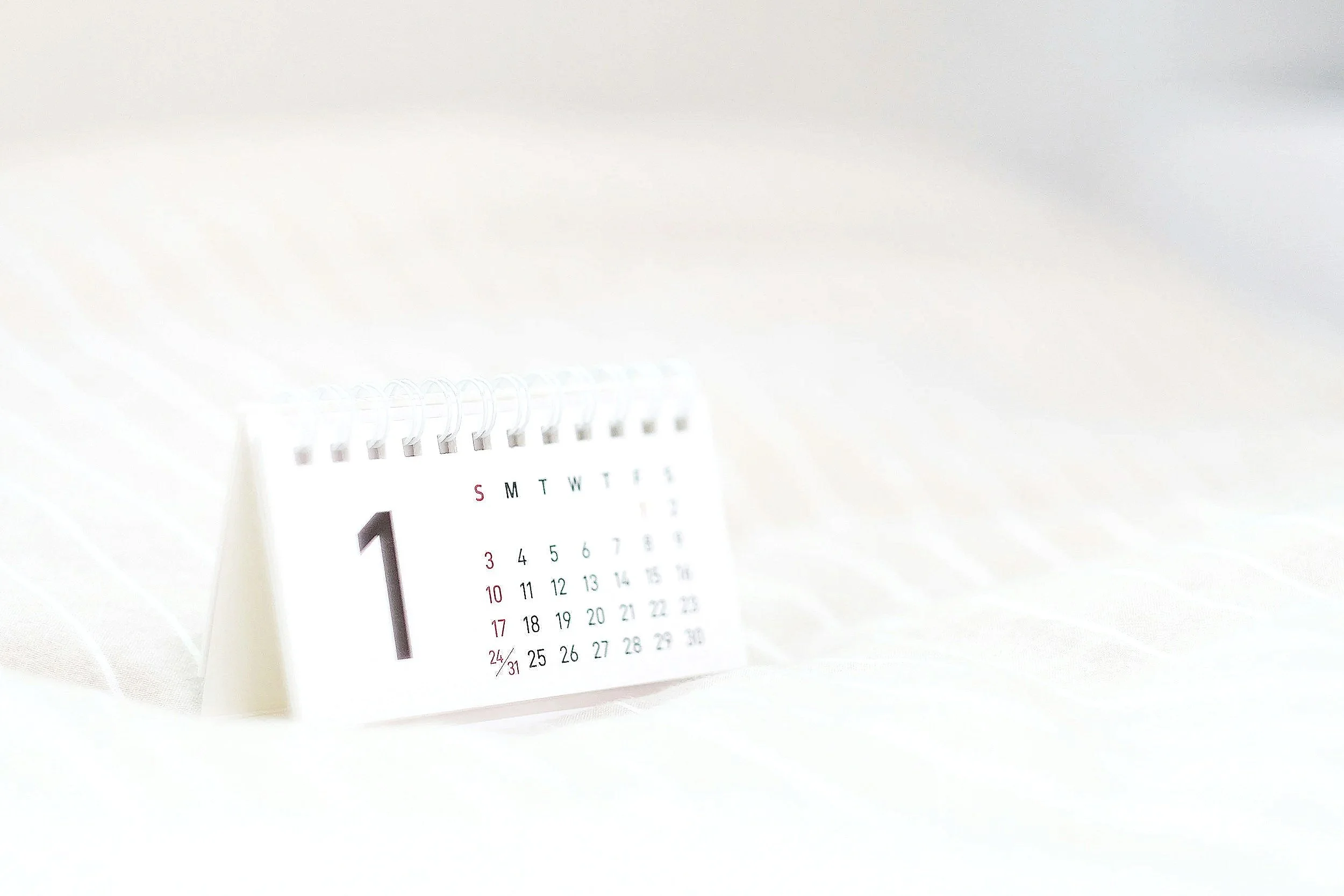 Desk calendar displaying January 2026 on a white surface with a soft background.