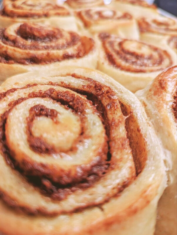 Close-up of freshly baked cinnamon rolls with swirled cinnamon filling.