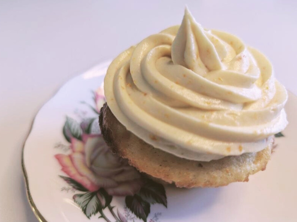 Cupcake with vanilla frosting on a decorative plate.
