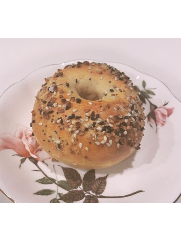 A donut topped with sprinkles and chopped nuts on a floral decorative plate.