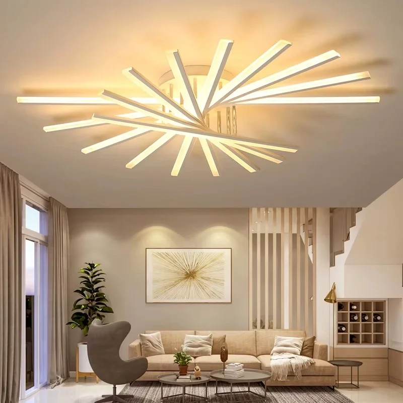 Modern living room with a large beige sofa, a gray accent chair, and a coffee table with plants and decorative items. A large abstract artwork hangs on the wall, and a stylish LED ceiling light fixture resembles a burst of light.