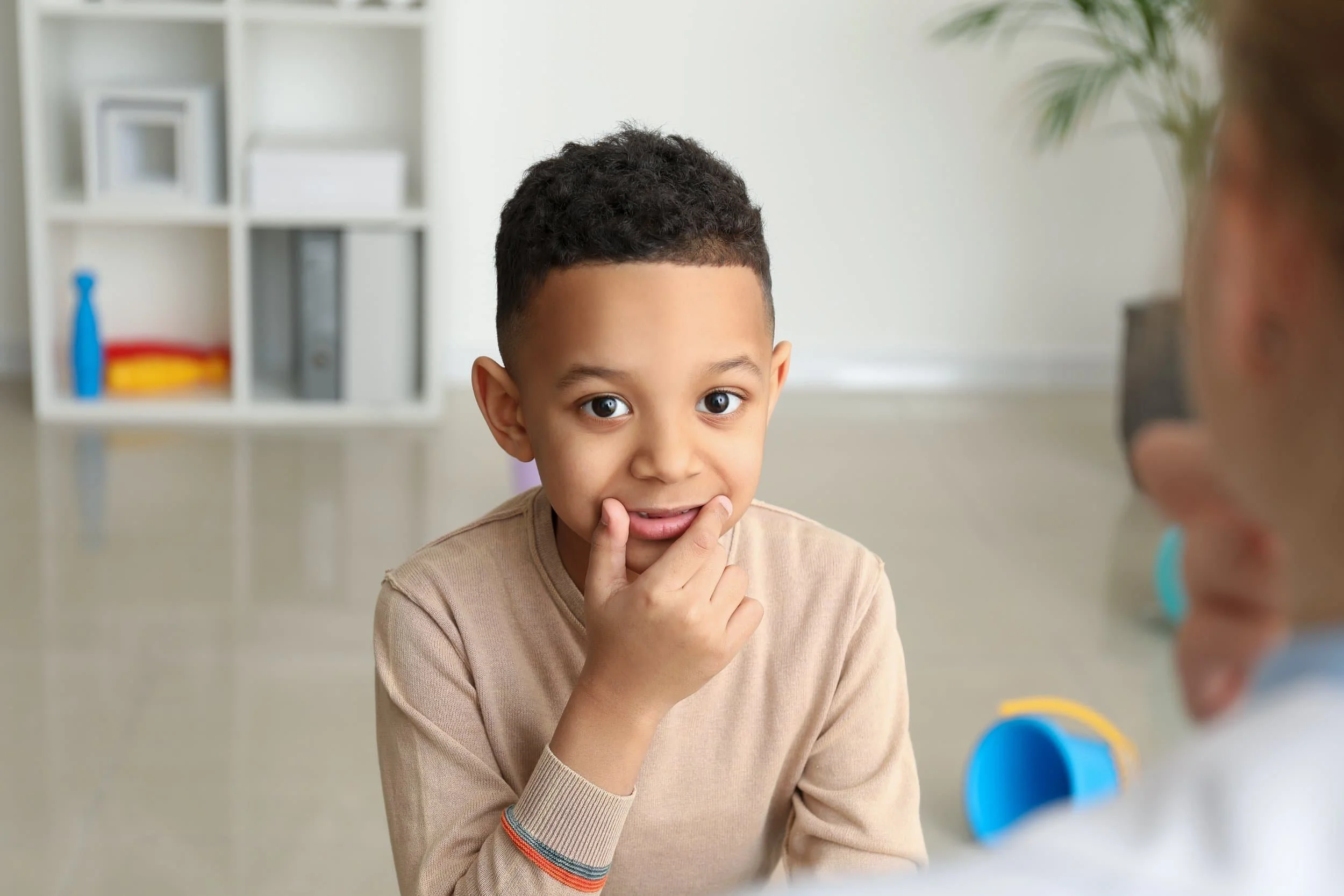 A cihld participating in speech articulation therapy providing self cues for sounds