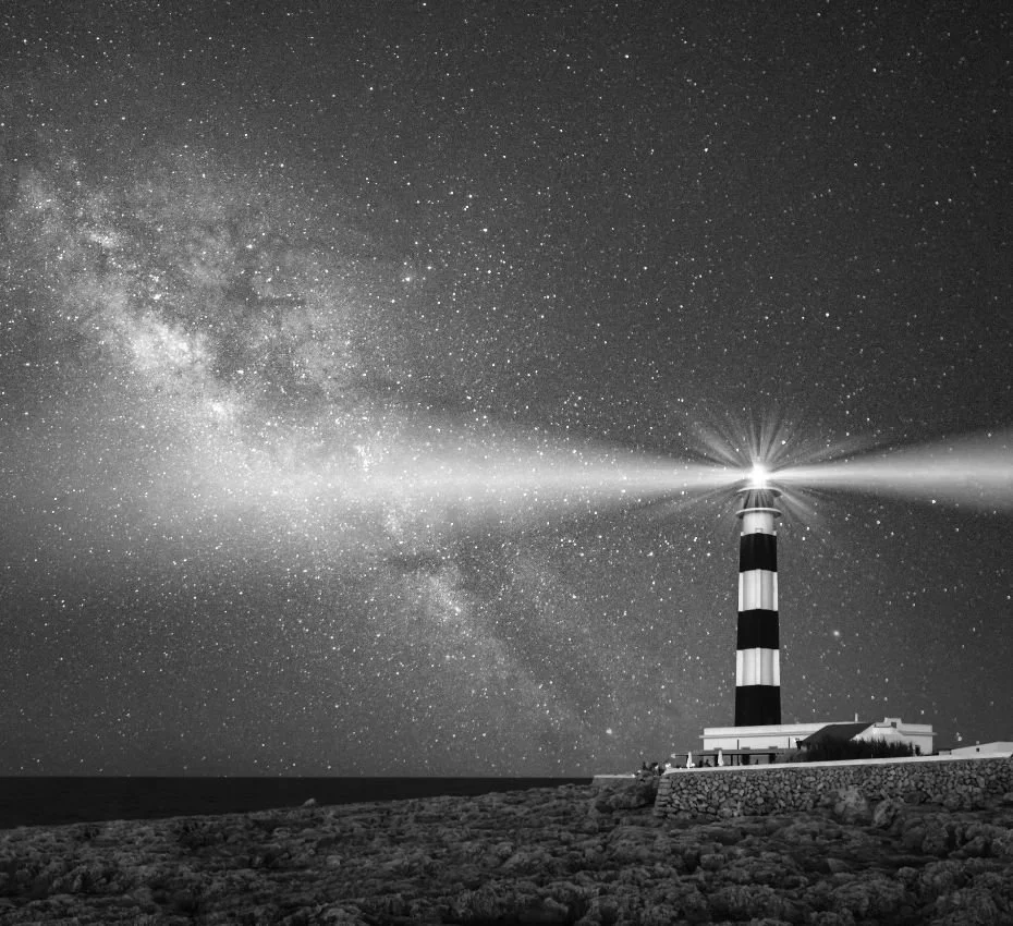 A lighthouse emitting a beam of light under a starry night sky.