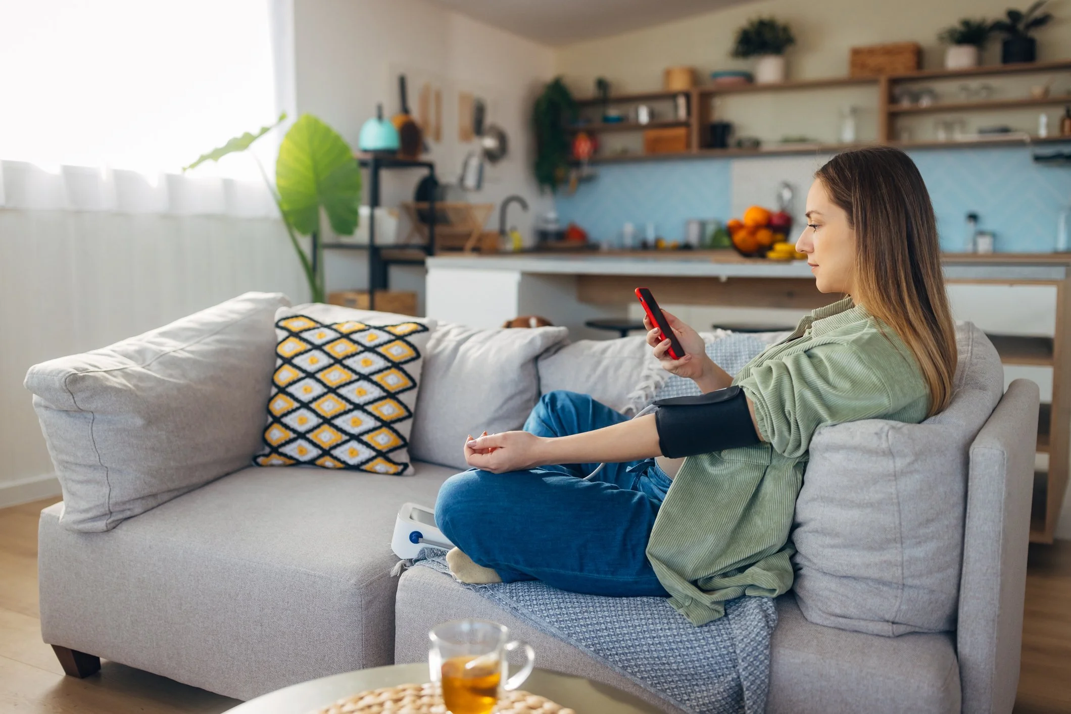 A pregnant woman sitting at home, reviewing her blood pressure measurements and trends, leaning more about her health with the Connura App