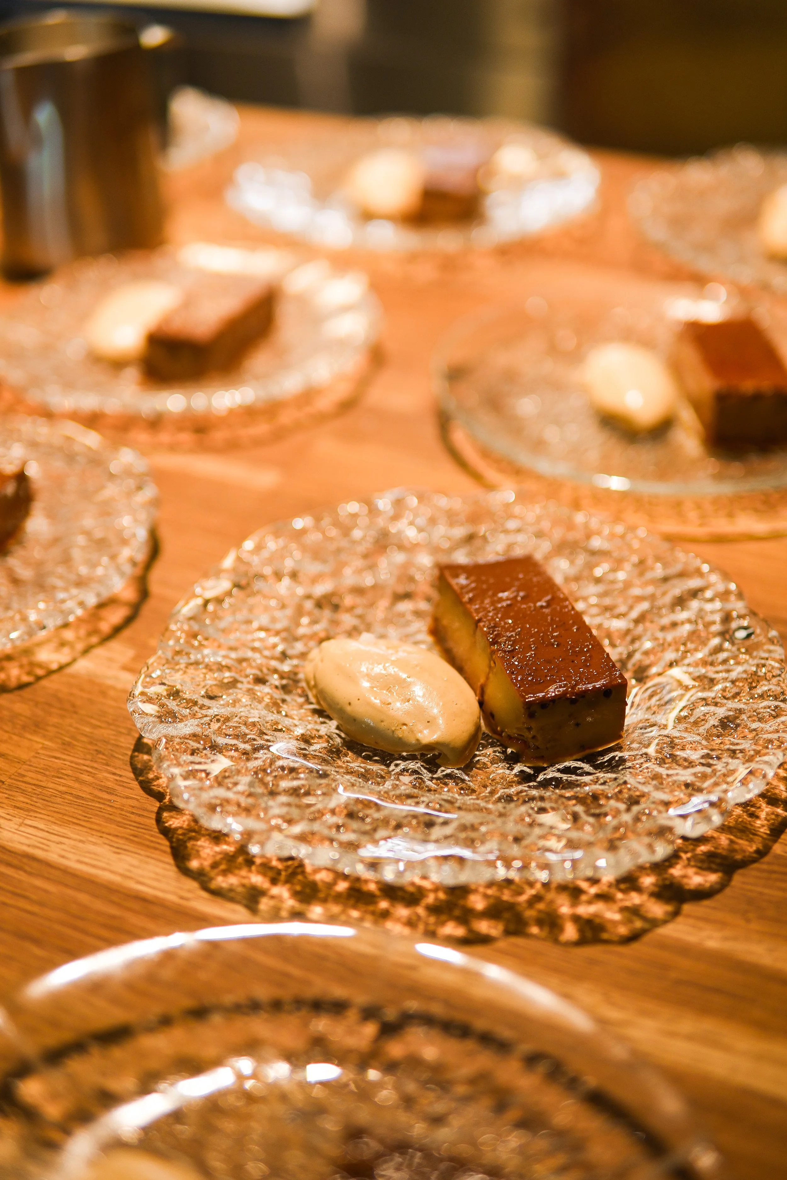 Dessert plates with chocolate cake and ice cream served on glass plates on wooden table.