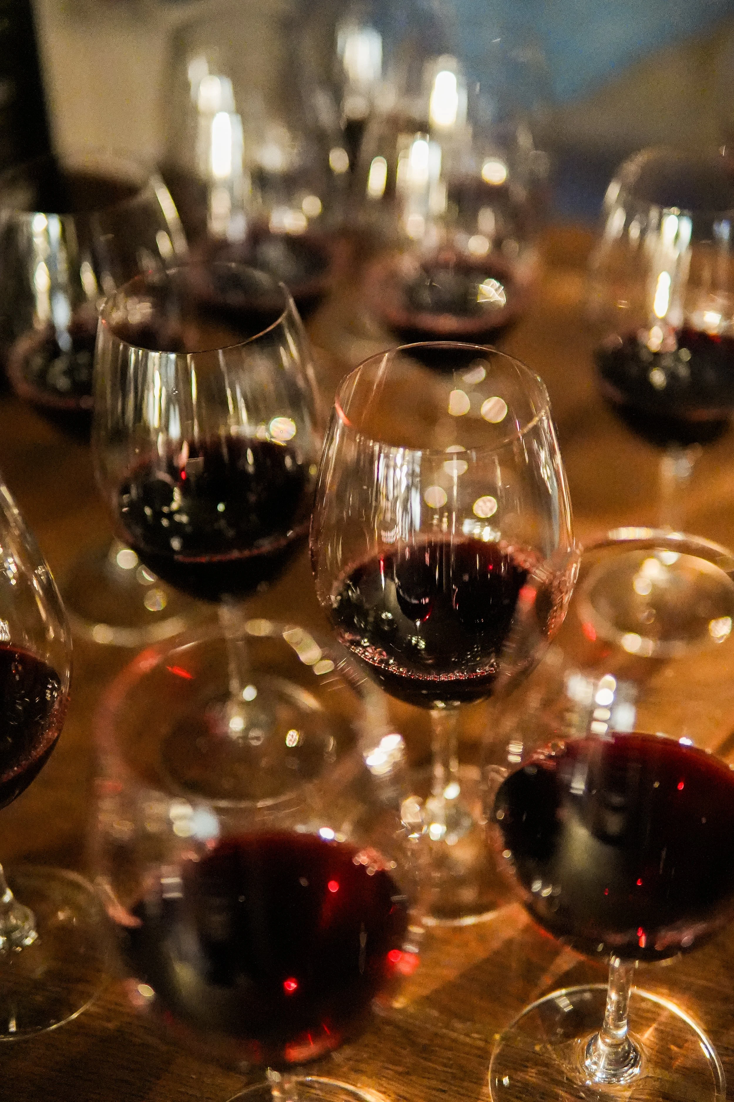 Multiple glasses of red wine on a table, some glasses are in focus while others are blurred.