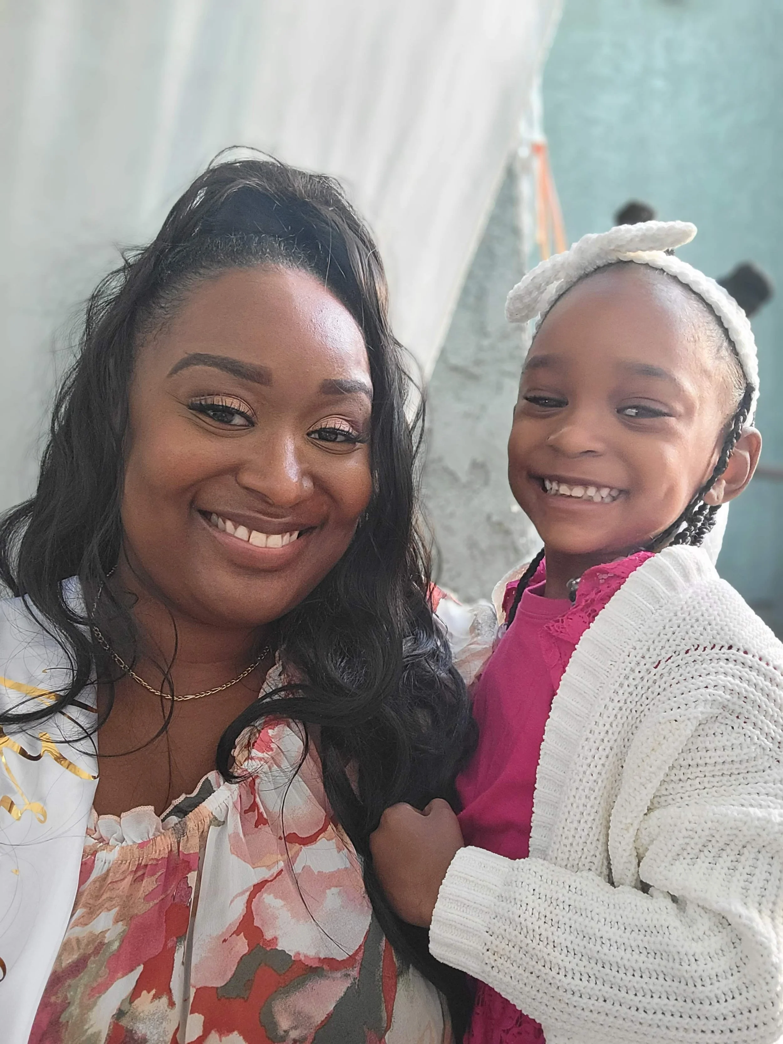 Smiling woman and young girl sharing a close moment indoors.