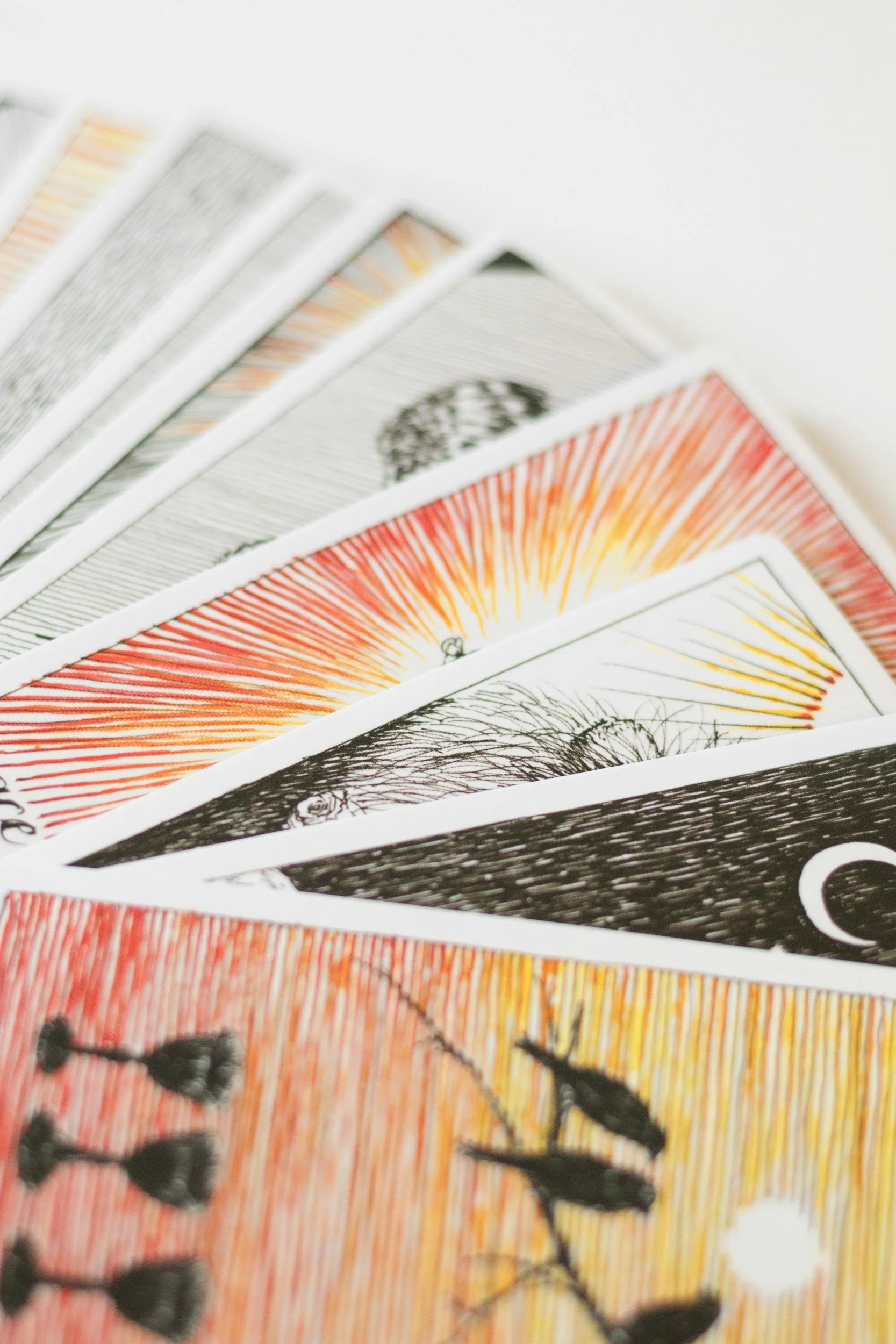 Close-up of colorful tarot or trading cards fanned out on a white surface.