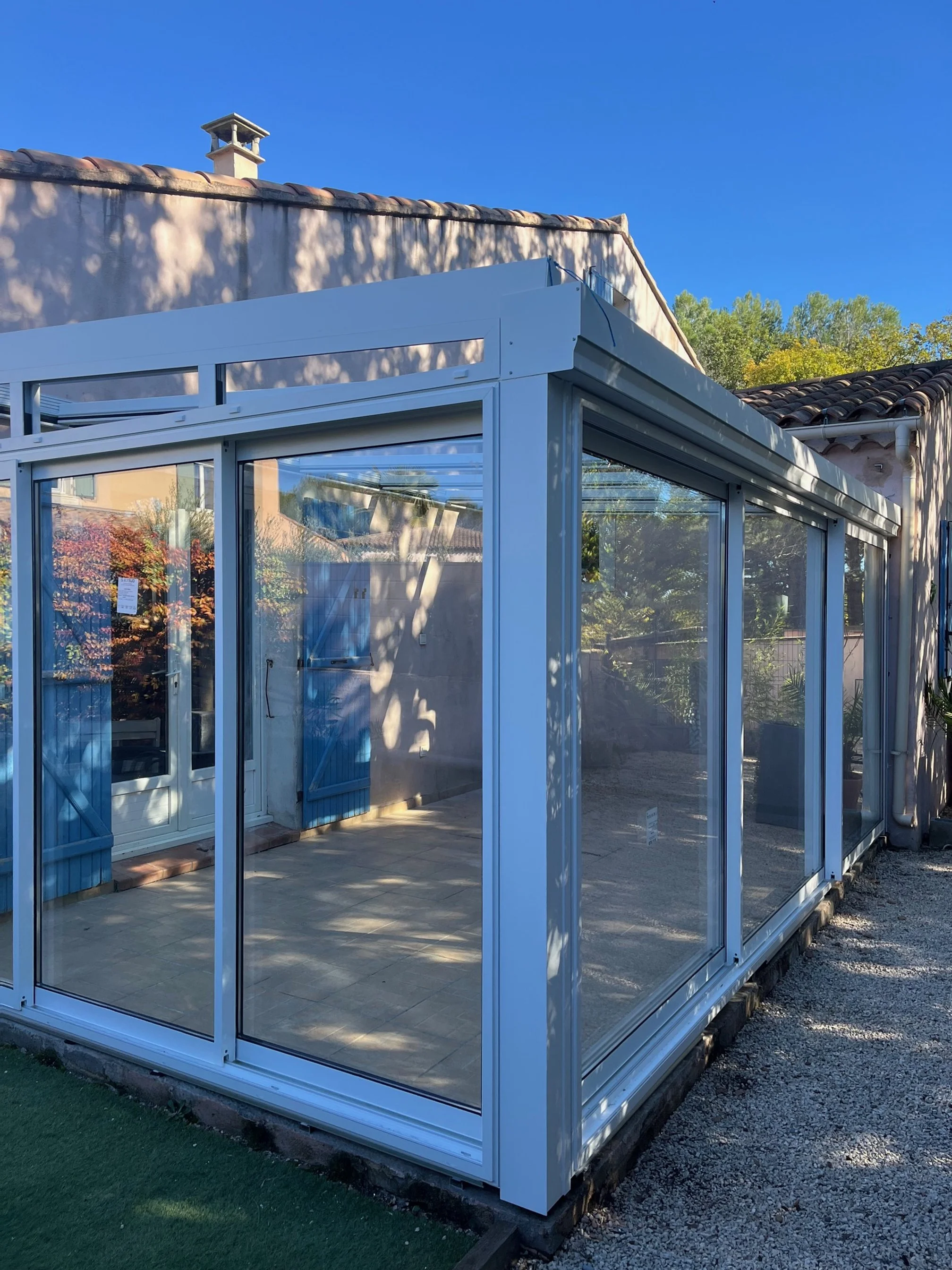 Une véranda aluminium, avec baies coulissante, toitures vitrées et panneaux