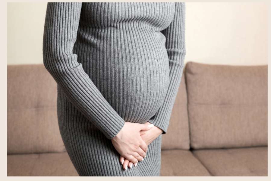 Pregnant woman with her hands resting on her bladder. Afraid of incontinence. Pregnancy incontinence. Urinary incontinence. Bladder leaking.
