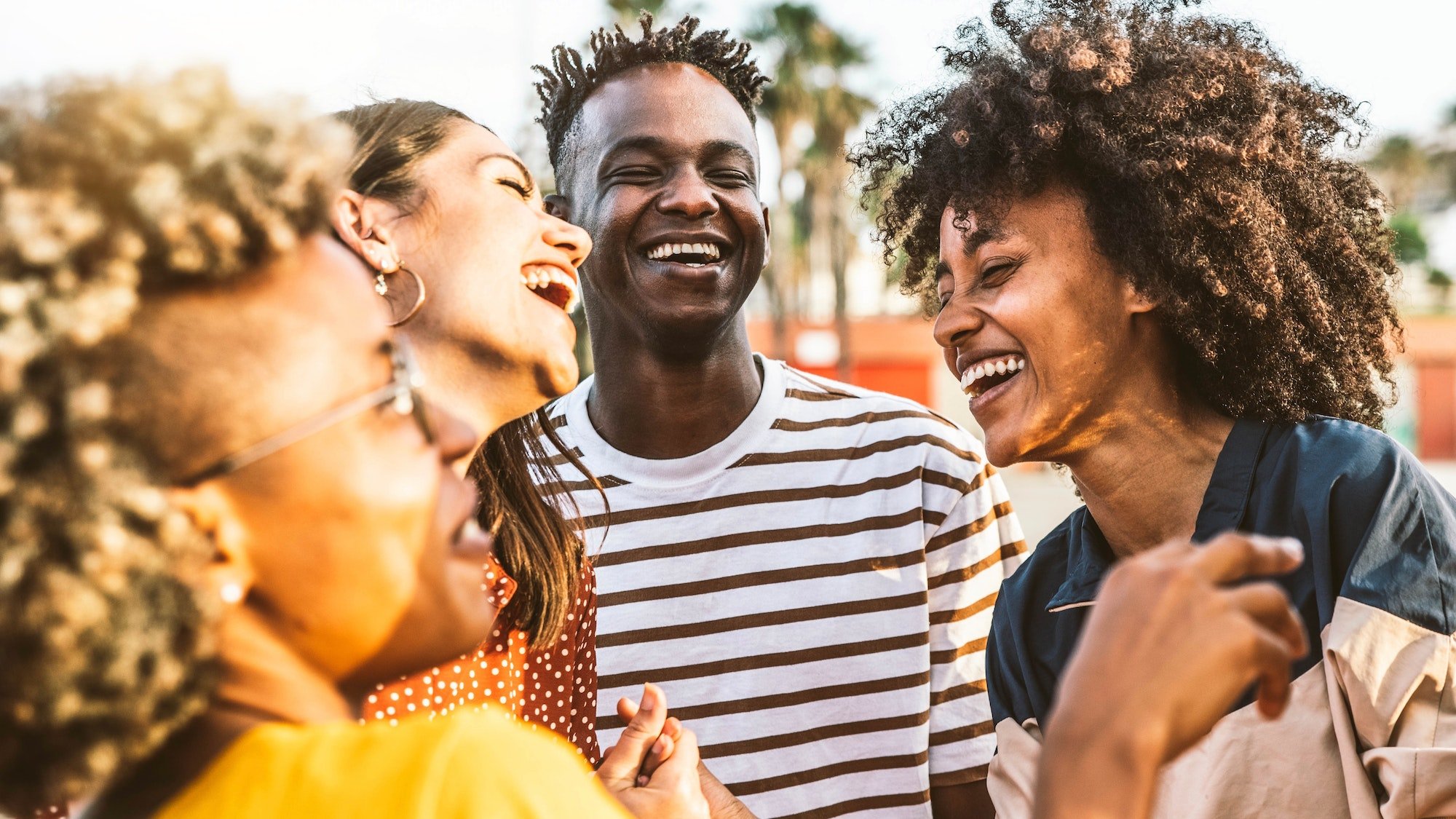 Four diverse friends laughing and enjoying each other's company outdoors.