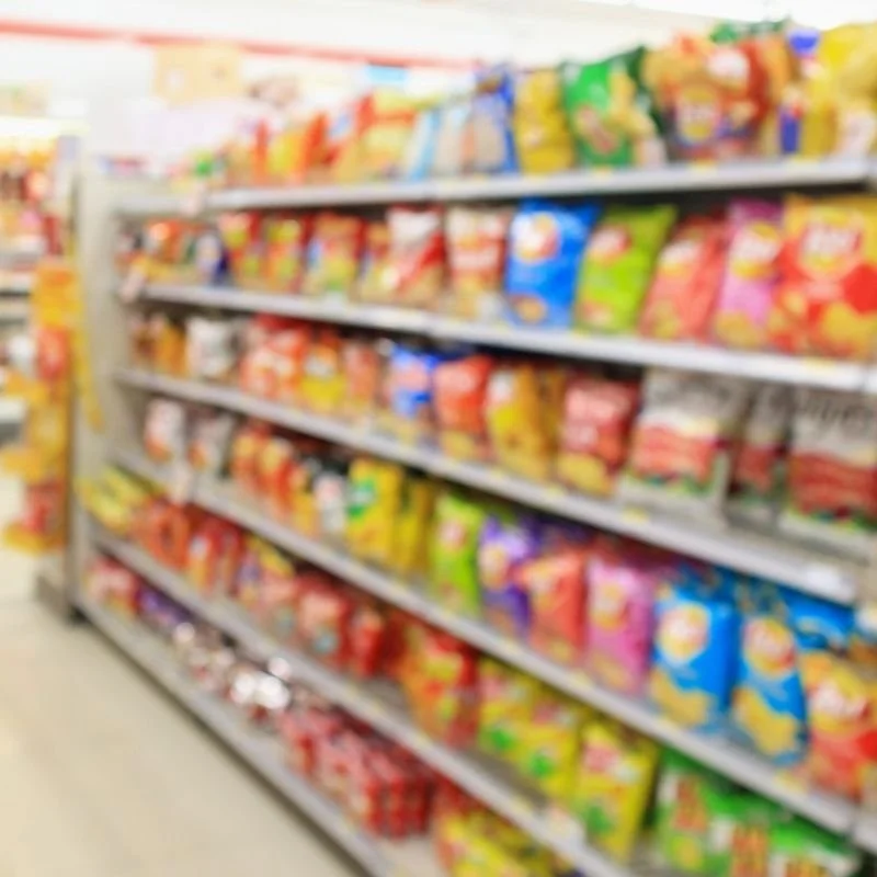 Blurred image of store shelves stocked with colorful snack packages.