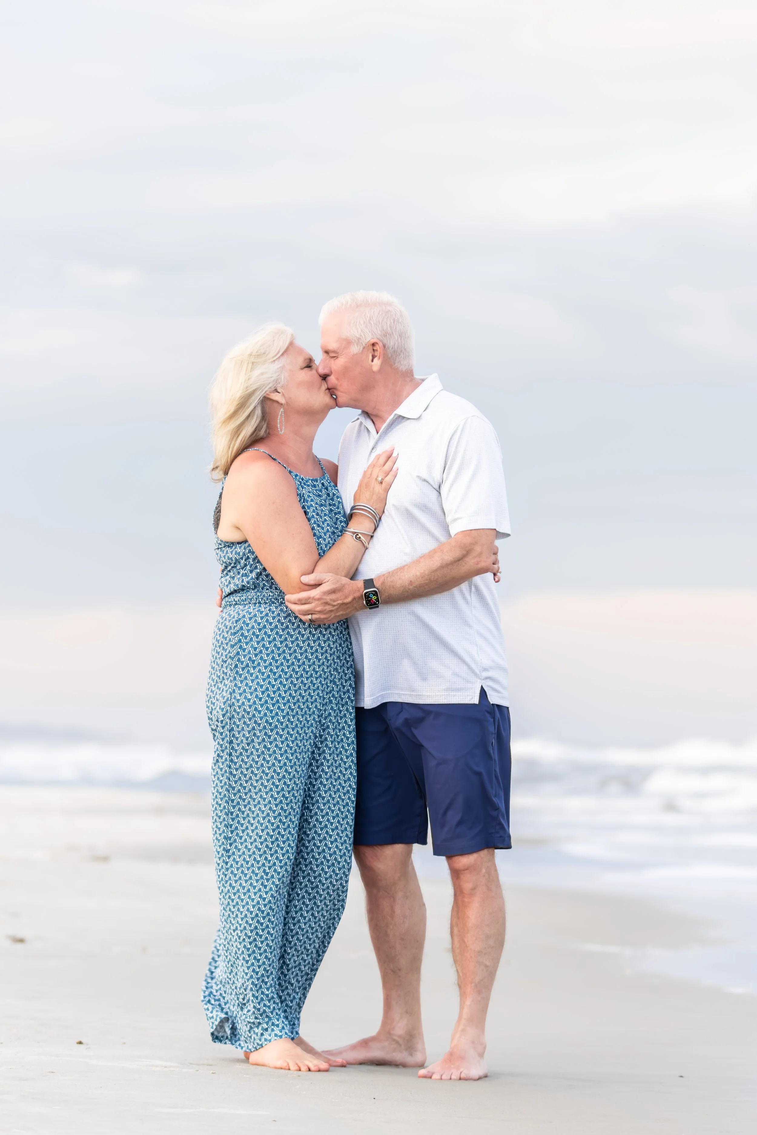 An elderly couple sharing a kiss on the beach