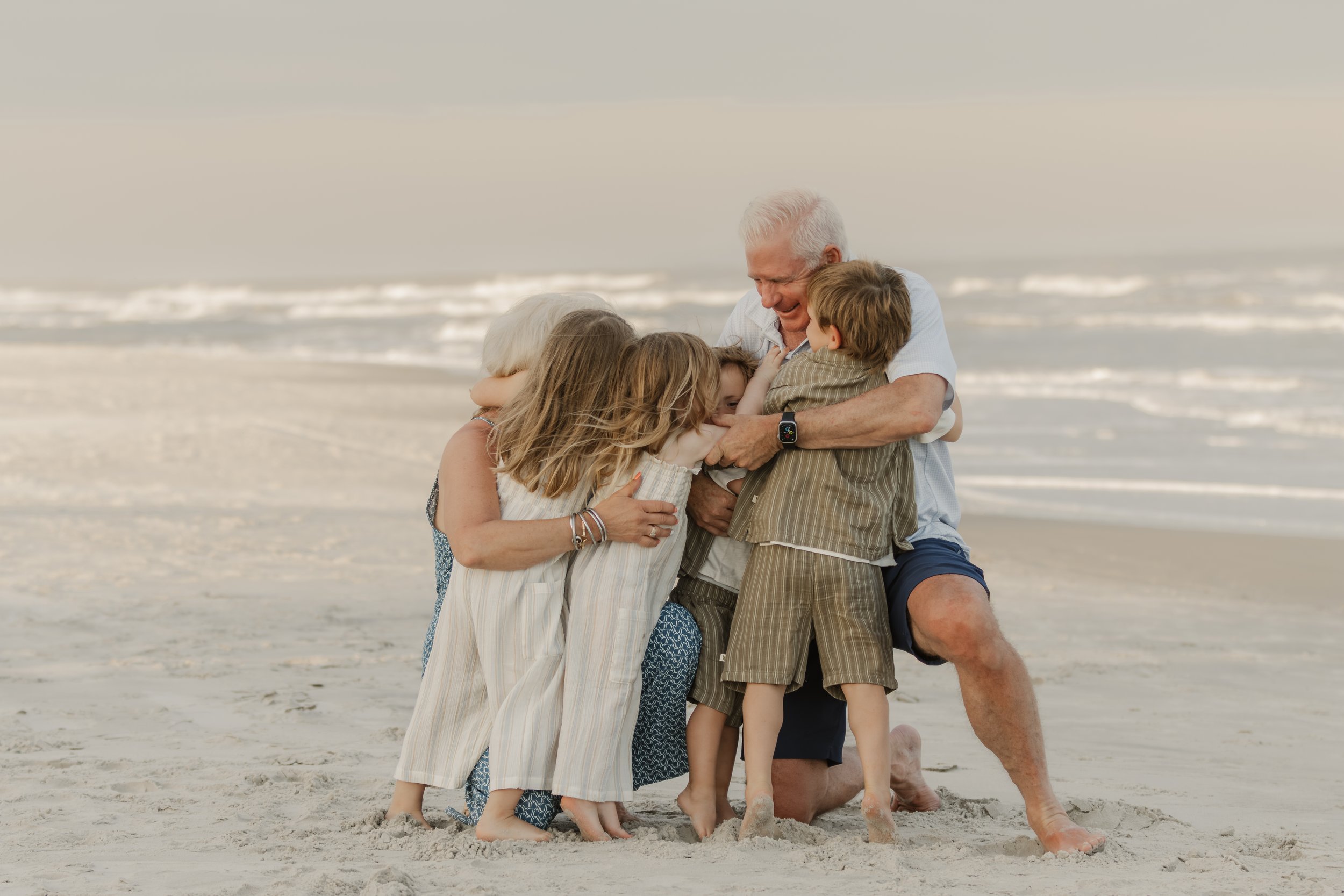 Grandparents and grandchildren hugging on the beach